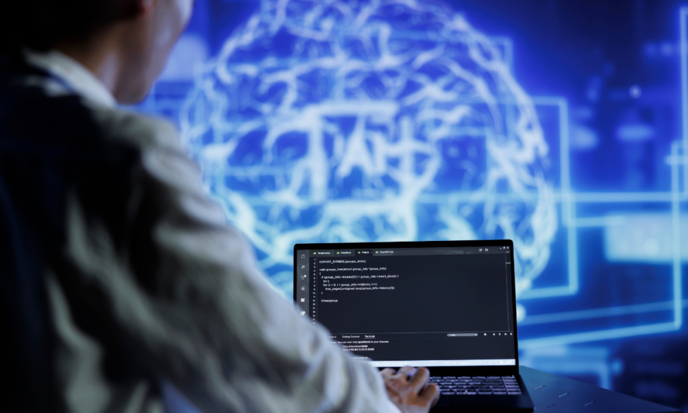 Sviluppatore che lavora al computer su codice di programmazione con un'immagine digitale di un cervello sullo sfondo, simbolo di intelligenza artificiale e apprendimento automatico.