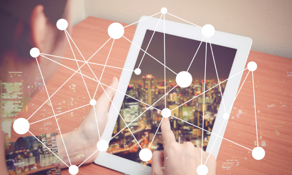 Foto di una persona che utilizza un laptop parzialmente coperta da una rete di punti connessi in modo da rappresentare l'interconnessione tra reti e dispositivi.